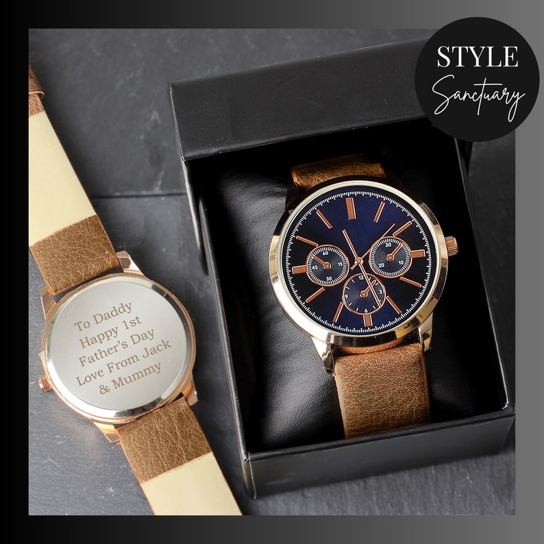 May include: A brown leather wristwatch with a gold-tone case and a blue face. The watch has a personalized message on the back that reads "To Daddy Happy 1st Father's Day Love From Jack & Mummy".