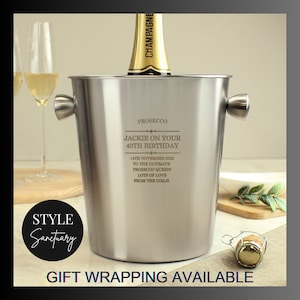 May include: Silver champagne bucket with a personalized inscription for a 40th birthday. The inscription reads "Jackie on your 40th Birthday 14th November 2023 To the ultimate Prosecco Queen! Lots of love from the girls!"