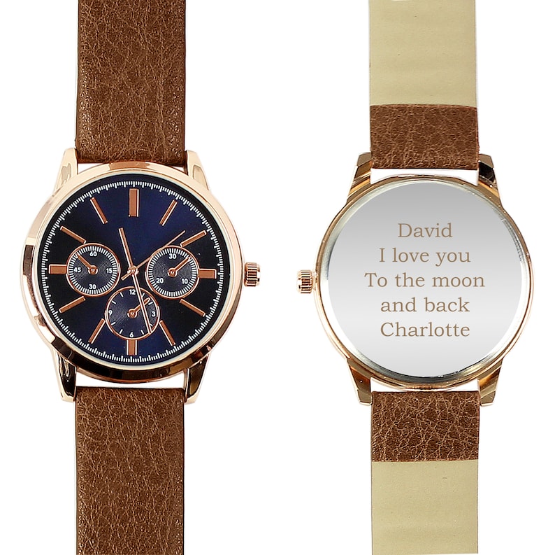 May include: A brown leather wristwatch with a rose gold case and a blue face. The back of the watch has an engraved message that reads "David I love you To the moon and back Charlotte".