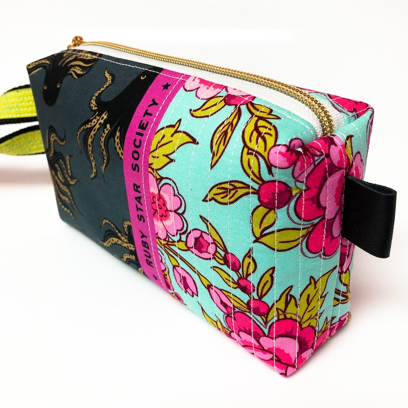 May include: A turquoise and pink floral print zippered pouch with a black strap and the text "Ruby Star Society" on the side.
