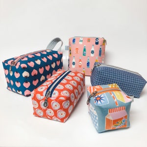 Pode incluir: Cinco bolsas de z&iacute;per diferentes com v&aacute;rios padr&otilde;es. As bolsas s&atilde;o feitas de tecido e t&ecirc;m uma variedade de cores e designs. As bolsas s&atilde;o de diferentes tamanhos e formas.