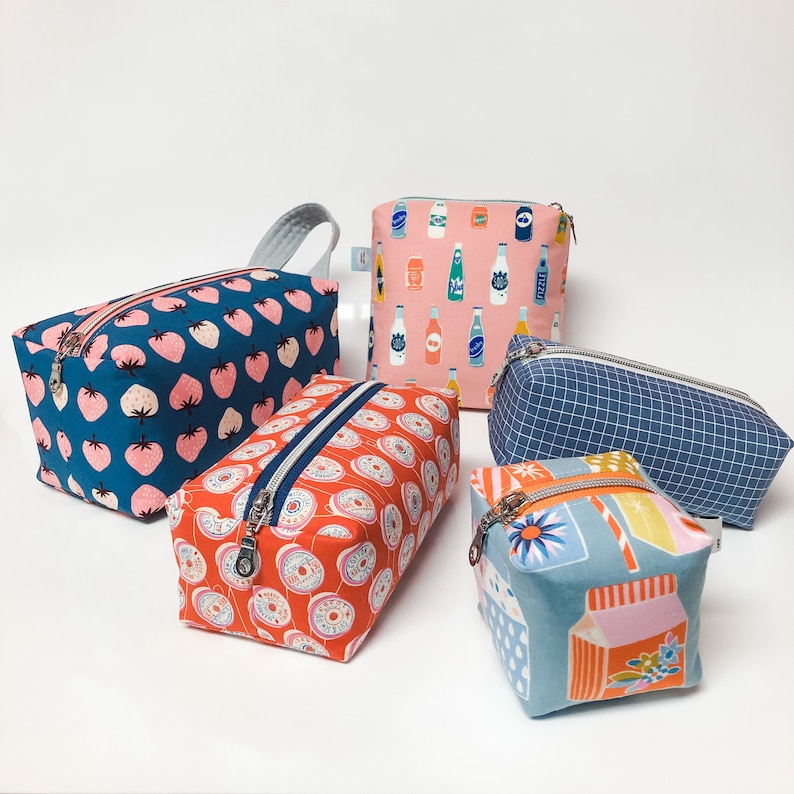 Pode incluir: Cinco bolsas de z&iacute;per diferentes com v&aacute;rios padr&otilde;es. As bolsas s&atilde;o feitas de tecido e t&ecirc;m uma variedade de cores e designs. As bolsas s&atilde;o de diferentes tamanhos e formas.