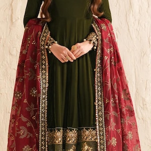 May include: An olive green dress with long sleeves and gold embellishments. A maroon shawl with gold floral patterns and trim is draped over the shoulders. The dress has a detailed hemline.