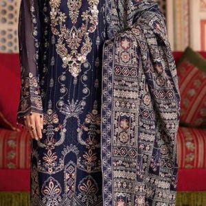 May include: A navy blue embroidered formal dress with a matching shawl. The dress features intricate gold and silver floral patterns. The shawl has a similar design. The model is wearing a gold headpiece and jewelry.