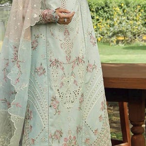 May include: A light blue embroidered dress with floral patterns and a matching sheer shawl. The dress features intricate detailing and a delicate design, perfect for special occasions. The dress is a soft, pastel color.