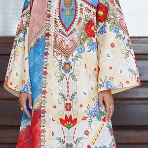 May include: A long, flowing dress with a vibrant floral pattern in red, blue, and yellow. The dress features a detailed design with intricate floral and geometric elements, and a matching scarf.