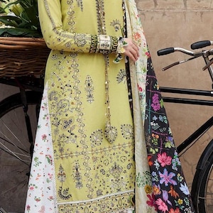 May include: A white ceramic mug with a black handle and the text "But First, Coffee" in a bold, black font. The mug is set against a blurred background, suggesting a cozy setting.