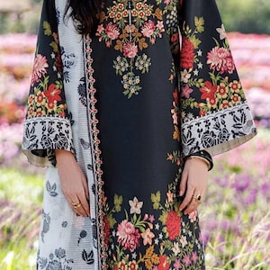 May include: Black floral print dress with long sleeves and a matching white and black patterned shawl. The dress features a vibrant floral design in red, pink, and yellow. The dress is a long, flowing style.