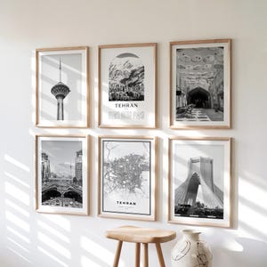 May include: Six framed black and white prints of Tehran, Iran, hang on a white wall. The prints feature images of landmarks, cityscapes, and a map. Each print is in a light-colored wooden frame. The word "TEHRAN" is printed on some of the prints.