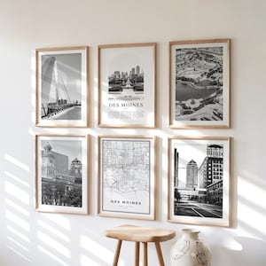 May include: Six framed black and white prints of Des Moines, Iowa, including cityscapes, a map, and architectural views. The prints are displayed on a white wall with a wooden stool and a decorative vase in the foreground.