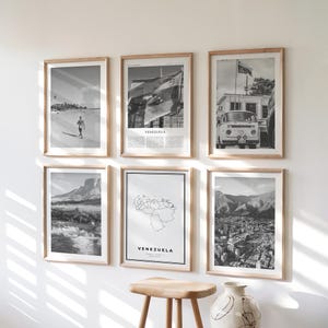 Op de afbeelding: Zes zwart-witfoto's met houten frames worden op een witte muur getoond. De foto's tonen scènes van een strand, een vlag, een vintage busje, een bergketen, een kaart van Venezuela en een stadsgezicht. Het woord "VENEZUELA" staat op twee van de foto's.