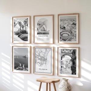 Op de afbeelding: Zes ingelijste zwart-wit prints van Valencia, Spanje, hangen aan een witte muur. De prints tonen architectuur- en landschapsfotografie, waaronder een kaart en stadsgezichten. De frames zijn gemaakt van lichtgekleurd hout.
