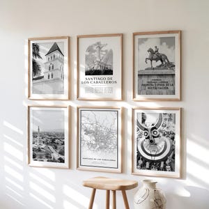 May include: A collection of six framed black and white art prints. The prints feature architectural landmarks, a map, and abstract designs. The frames are made of light-colored wood, and the prints are displayed on a white wall.