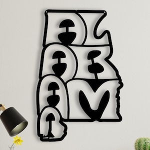 Puede incluir: Arte de pared de metal negro que deletrea la palabra "DREAM" en una fuente estilizada. La obra de arte est&aacute; montada en una pared blanca sobre un escritorio de madera con una l&aacute;mpara, libros, un reloj y plantas en macetas.