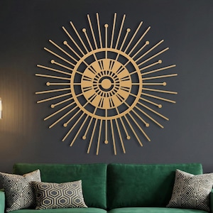 Gold art deco sunburst metal wall art, mid century modern starburst decor over green velvet couch in dark living room.
