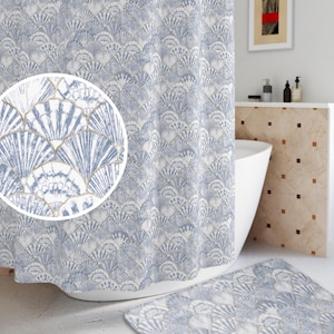 May include: A blue and white shower curtain with a seashell pattern. The shower curtain is hanging in a bathroom with a white bathtub and a white tiled wall.