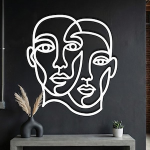 White abstract face wall art, minimalist line art sculpture on black industrial wall.
