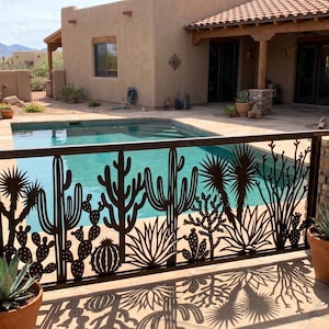 May include: A decorative metal fence with a desert cactus design surrounds a swimming pool. The fence is dark brown and the pool water is a light blue. The background includes a house with a terracotta tile roof and potted plants.