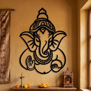 May include: A black metal wall sculpture of Ganesha, the Hindu deity. The artwork shows the elephant-headed god with detailed features. It is mounted on a tan wall, with a wooden table and other decorative items below. The table has a length of approximately 100 cm.
