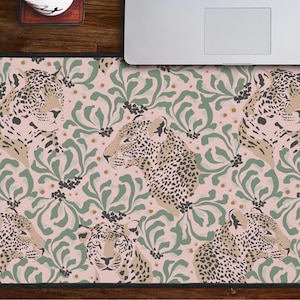 May include: A pink and green mouse pad with a repeating pattern of leopard print and leafy designs. The mouse pad is made of a soft, smooth material and is perfect for use with a computer mouse.