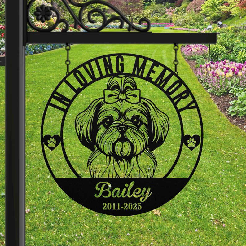 Puede incluir: Letrero conmemorativo de metal negro con una silueta de perro Shih Tzu, las palabras "IN LOVING MEMORY" y el nombre "Bailey" con los a&ntilde;os 2011-2025. El letrero incluye detalles de huellas de patas y cuelga de un soporte decorativo.