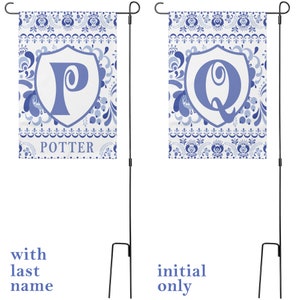 May include: Two blue and white garden flags with a floral pattern. The flag on the left has a blue letter "P" in a white shield with the word "POTTER" below it. The flag on the right has a blue letter "Q" in a white shield. Both flags are attached to black metal poles.
