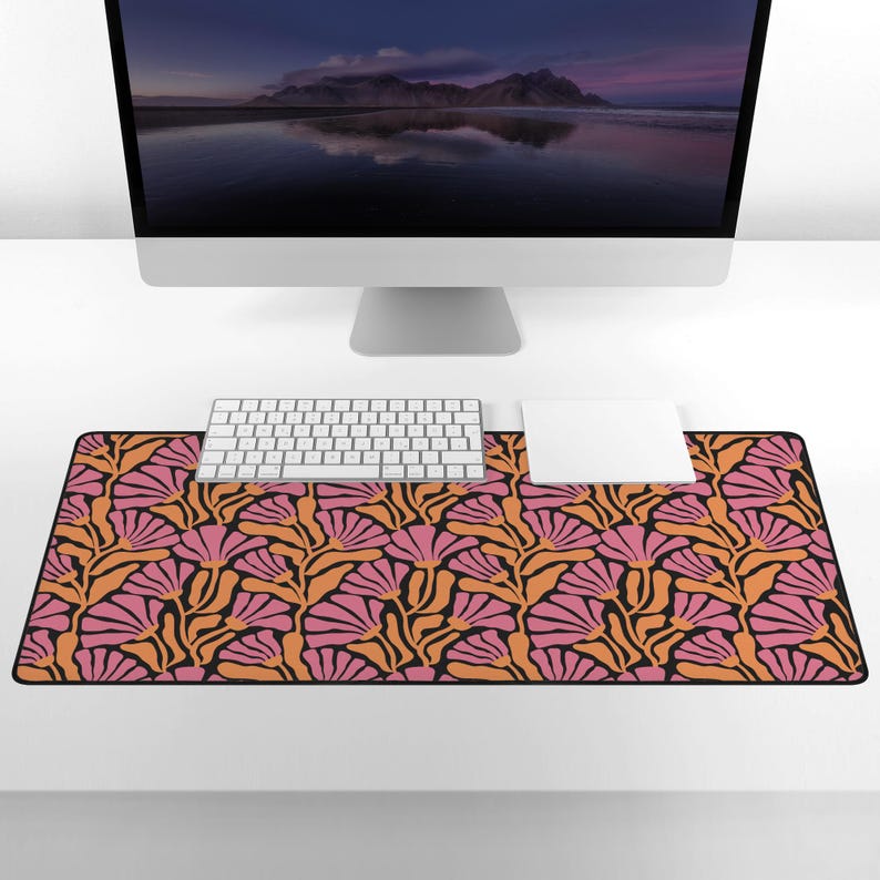 May include: A black desk mat with a pink and orange floral pattern. The mat is designed to protect your desk surface and provide a comfortable workspace.