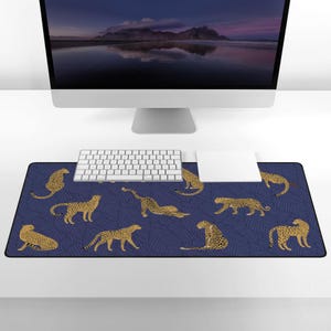 May include: A blue and gold leopard print mouse pad with a white keyboard and mouse on a white desk.