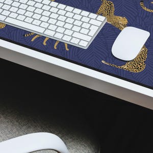 May include: A blue and gold mousepad with a cheetah print design. A white keyboard and mouse are on top of the mousepad.
