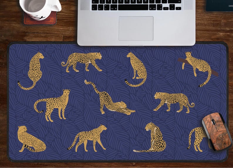 May include: A blue and gold mouse pad with a repeating pattern of leopards on a leafy background. The mouse pad is designed for use with a computer mouse.