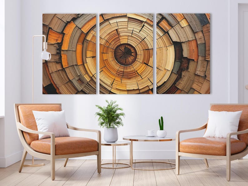 May include: A triptych of abstract art panels featuring a concentric circular design in shades of brown, orange, and yellow, resembling a cross-section of a tree trunk. The artwork hangs above two tan armchairs with white pillows.