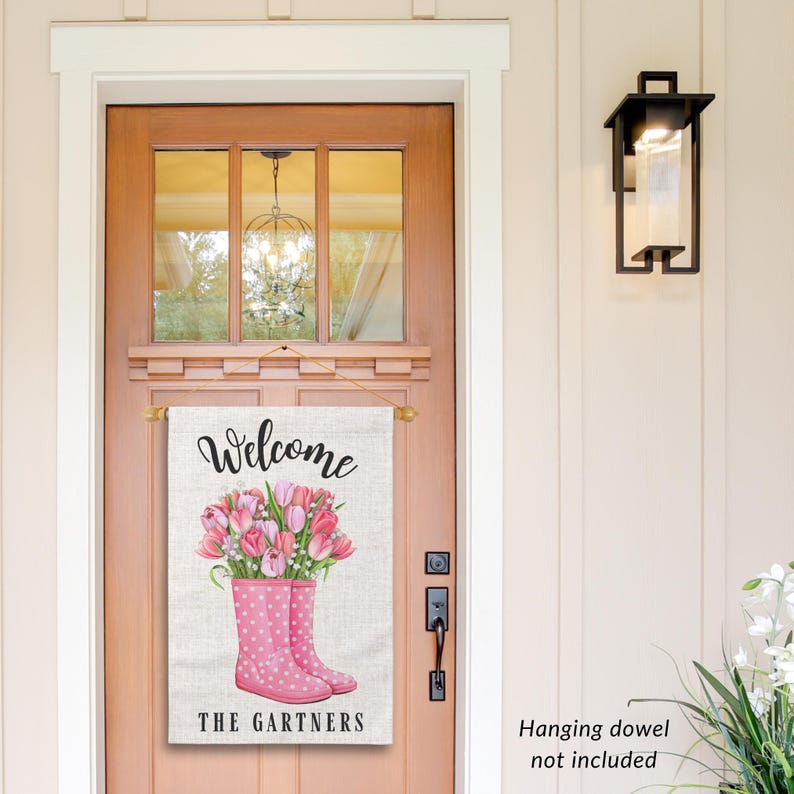 May include: A welcome sign with a burlap background featuring pink rain boots with a bouquet of pink tulips. The sign reads "Welcome The Gartners".