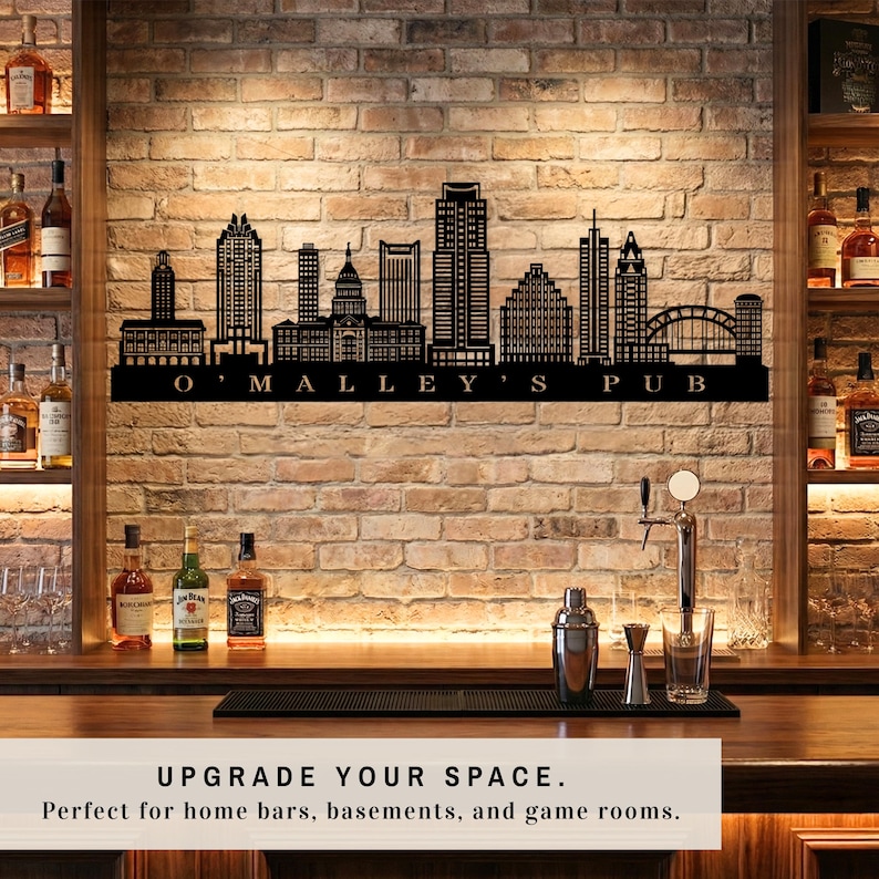 May include: Black metal wall art showing a city skyline with the text "O'Malley's Pub". The artwork is mounted on a brick wall, above a bar with barware. The image includes the text "UPGRADE YOUR SPACE."