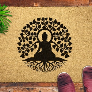 May include: A brown doormat with a black silhouette of a meditating Buddha figure inside a tree with roots. The tree has many leaves and the Buddha is sitting in a lotus position.