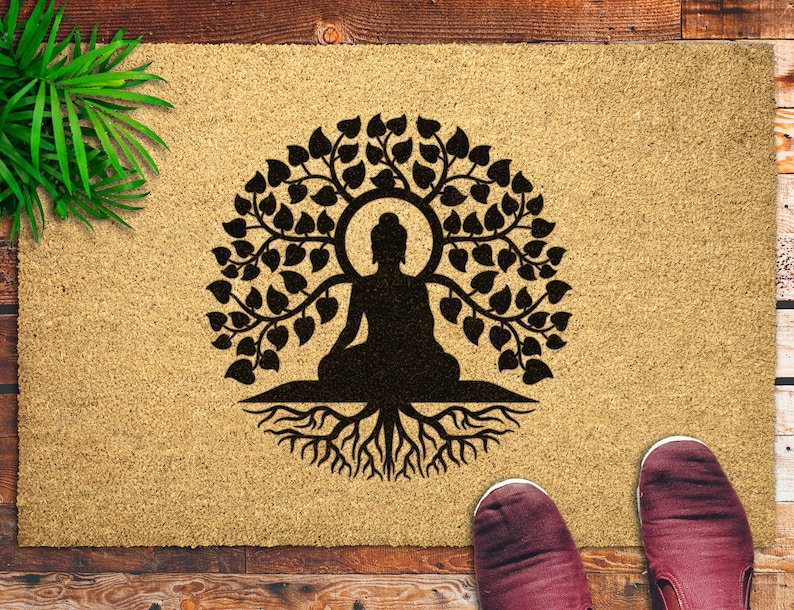 May include: A brown doormat with a black silhouette of a meditating Buddha figure inside a tree with roots. The tree has many leaves and the Buddha is sitting in a lotus position.