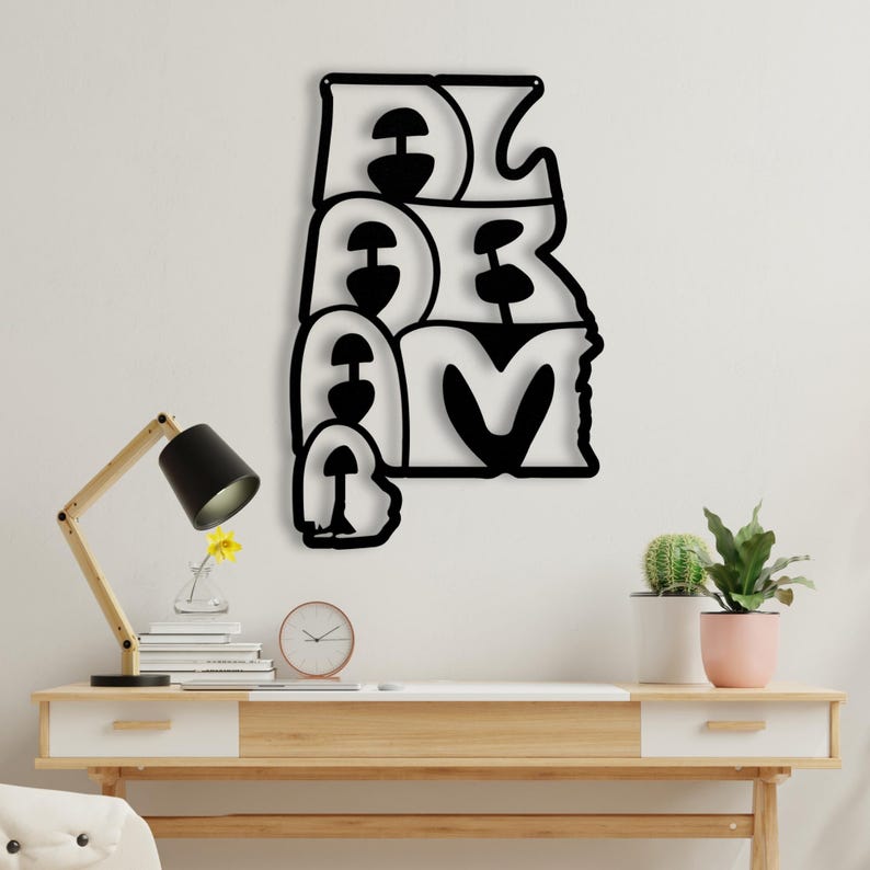 Puede incluir: Arte de pared de metal negro que deletrea la palabra "DREAM" en una fuente estilizada. La obra de arte est&aacute; montada en una pared blanca sobre un escritorio de madera con una l&aacute;mpara, libros, un reloj y plantas en macetas.