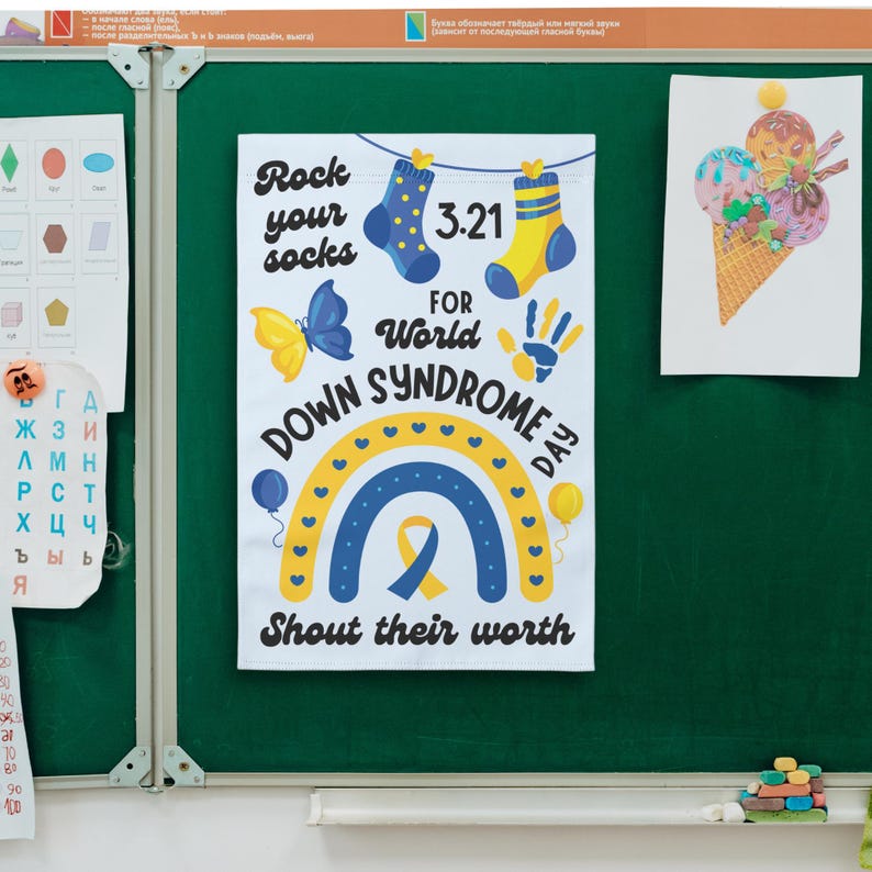 K&ouml;nnte beinhalten: Ein wei&szlig;es Schild mit einem blauen und gelben Regenbogen, einem gelben Band und dem Text "Rock your socks 3.21 for World Down Syndrome Day Shout their worth".