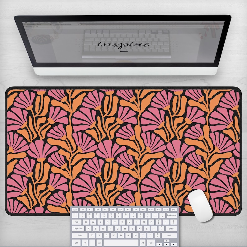 May include: A black desk mat with a floral pattern featuring pink and orange flowers on a black background. The mat is designed to protect your desk surface and provide a smooth surface for your mouse.