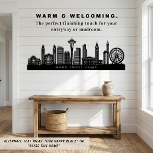 May include: Black metal wall art featuring a city skyline with the words "HOME SWEET HOME". The art piece includes the text "WARM & WELCOMING" and "The perfect finishing touch for your entryway or mudroom."