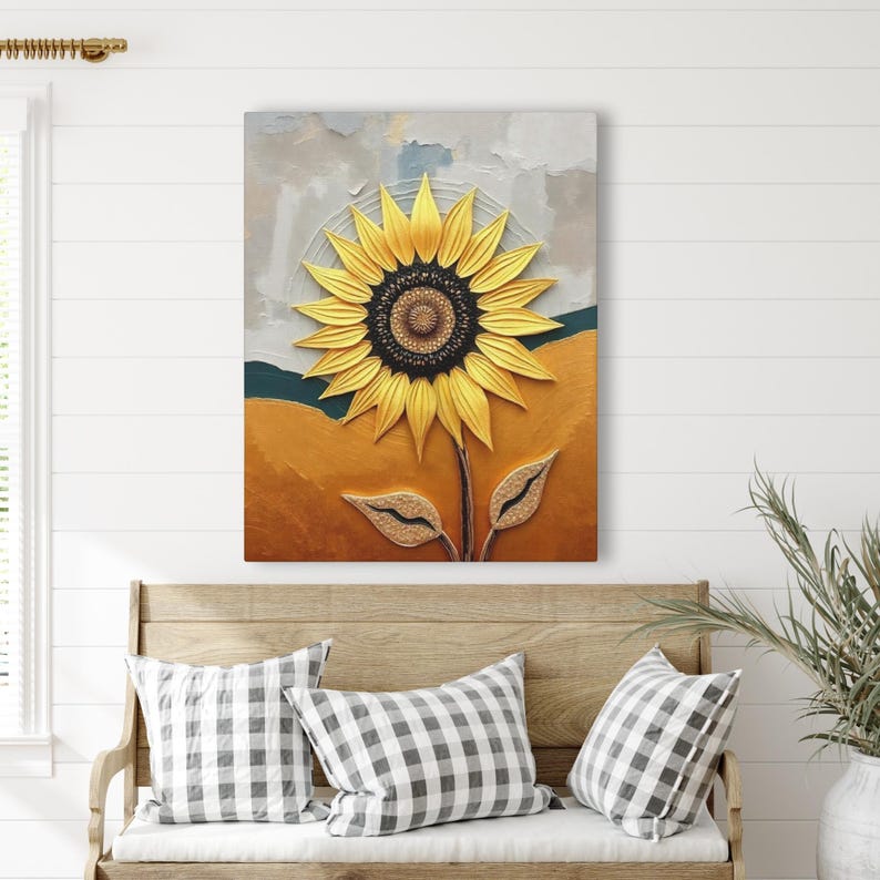 Puede incluir: Una obra de arte en lienzo texturizado que representa un girasol detallado. El girasol tiene p&eacute;talos de color amarillo brillante y un centro marr&oacute;n oscuro. El fondo presenta un dise&ntilde;o abstracto en oro, verde azulado y gris. La obra de arte se exhibe sobre un banco de madera con cojines a cuadros.