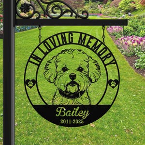 Puede incluir: Un letrero de metal negro con las palabras "IN LOVING MEMORY" que rodean una ilustraci&oacute;n de un perro. El nombre del perro, "Bailey", y las fechas "2011-2025" est&aacute;n debajo. Corazones con huellas de patas a ambos lados del perro.