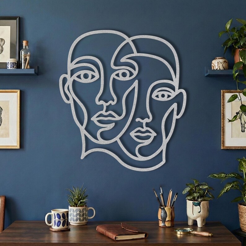 Silver wire wall art, abstract face sign on blue wall.