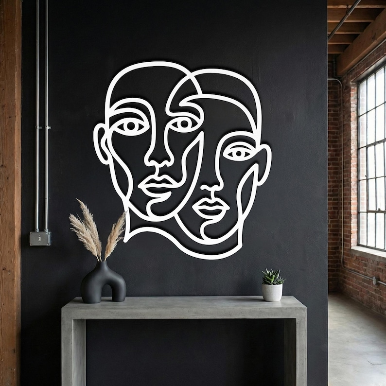 White abstract face wall art, minimalist line art sculpture on black industrial wall.