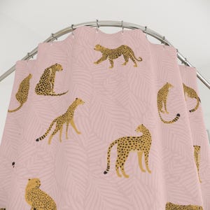 May include: Pink shower curtain with a repeating pattern of brown and black cheetahs on a pink background with a leaf pattern.