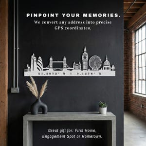 May include: A silver metal London skyline wall art piece. The artwork features iconic landmarks like the Tower Bridge, Big Ben, and the London Eye. The text reads "PINPOINT YOUR MEMORIES" and "Great gift for: First Home, Engagement Spot or Hometown."