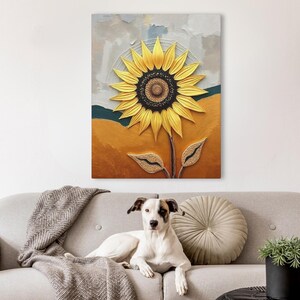 Puede incluir: Pintura texturizada de un girasol amarillo y centro marr&oacute;n oscuro. El fondo presenta tonos dorados, verde azulado y grises. La obra de arte se exhibe sobre un sof&aacute; gris con un perro.