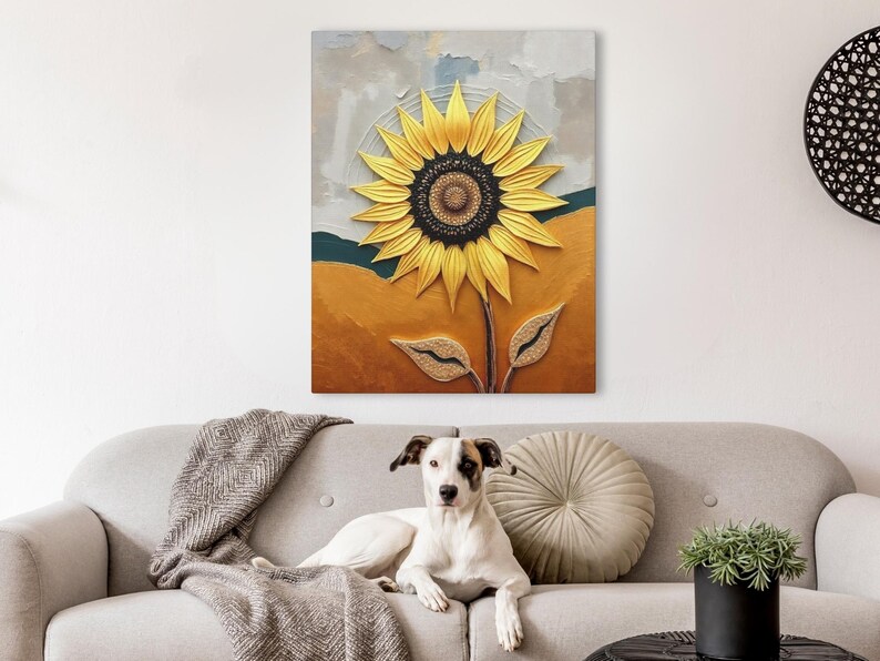 Puede incluir: Pintura texturizada de un girasol amarillo y centro marr&oacute;n oscuro. El fondo presenta tonos dorados, verde azulado y grises. La obra de arte se exhibe sobre un sof&aacute; gris con un perro.