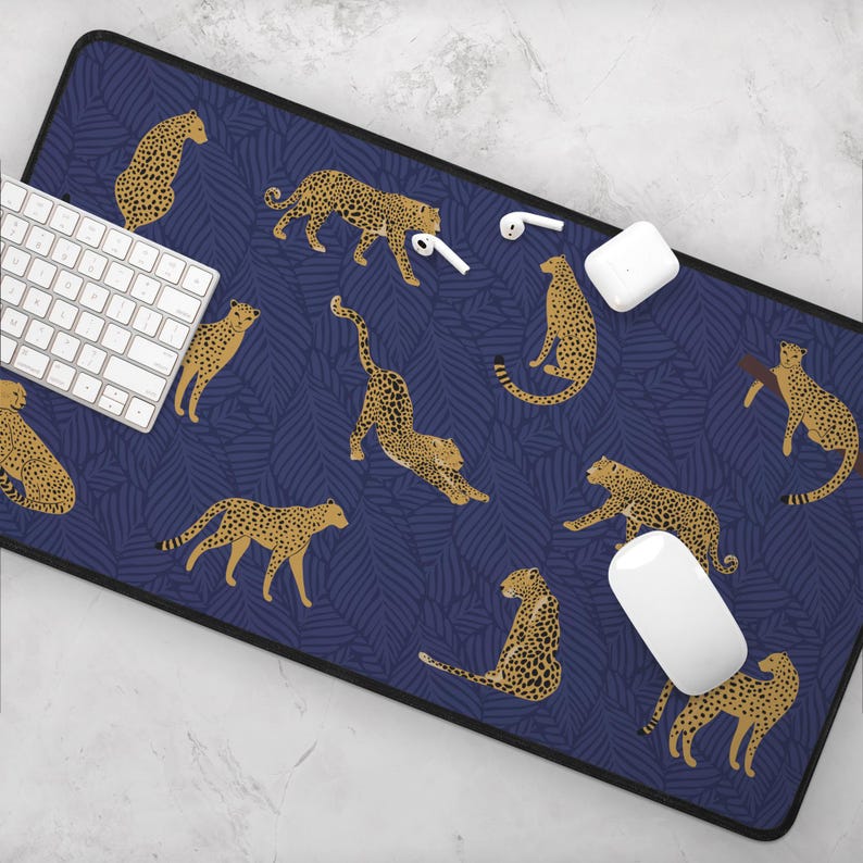 May include: A blue and gold mousepad with a repeating pattern of leopards on a dark blue background with palm leaves.
