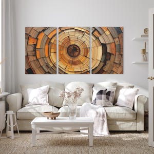 May include: A triptych wall art piece featuring a close-up of a cross-section of a tree trunk. The artwork displays concentric rings in shades of brown, orange, and tan, creating a natural, textured pattern. The art is displayed above a beige sofa.