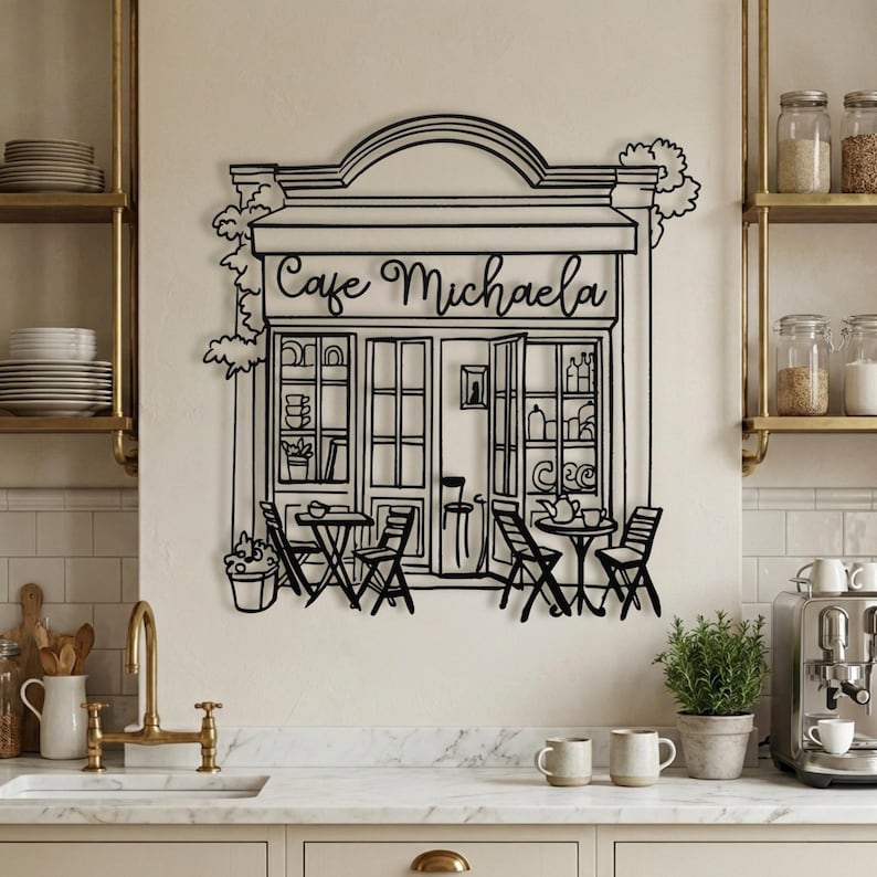 Personalized black metal cafe sign with "Cafe Michaela" script text hanging in a modern farmhouse kitchen.